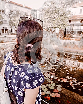 Female travel looks on the buildings and water in the center square of the city.