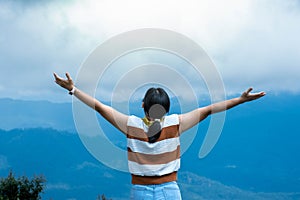 Female traveler enjoying the beauty of nature on the mountain looking at the lush trees in the tropical forest. Hipster woman