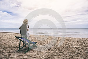 A female traveler with hat and backpack standing alone on the beach