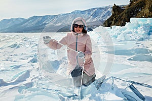 A female traveler holds an ice floe transparent as glass in her hands.