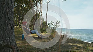 Female traveler sitting on camping chair and admires ocean view