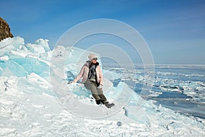 A female traveler is sitting on a huge block of ice. Hummocks on the ice