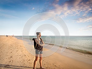 Female traveler is taking on mobile at the beach of Morro Jable, Fuerteventura - copy space