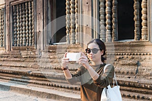 Female traveler taking photo with her smartphone in angkor wat cambodia