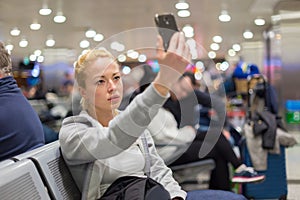 Female traveler taking selfie on airport.