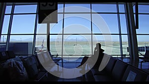 Female Traveler Talking on Mobile Phone While Waiting in Airport. Silhouette. Silhouette of Female Traveler waiting for