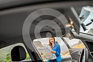Female traveler with toursit map near the car