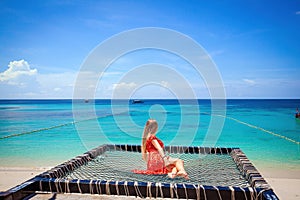 Female traveler unwinding on a hammock on tropical beach.
