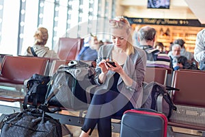 Female traveler using cell phone while waiting on airport.