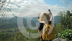 Female traveler using mobile phone taking selfie while solo travel on mountains