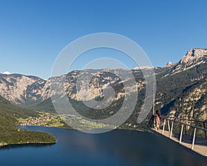 Female traveler on the viewpoint looking at a river and forested rocky hills in Hallstatt