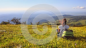 Female traveller with backpack making photo of mountain lanscape under blue sky