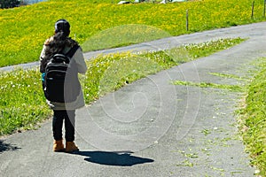 Female traveller with backpack walking along trail of green road