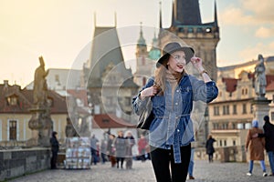 Female traveller tourist on the Charles Bridge in Prague, Czezh Repubic. Stylish beautiful young woman earing black hat