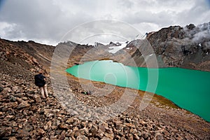 Female trekker backpacker hiking at bank of Beautiful landscape of turquoise Ala-Kul Lake, Karakol valley, Issyk-kul region, Ala-