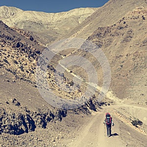 Female trekker walking alone though mountain desert.