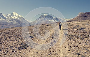 Female trekker walking alone though mountain desert.