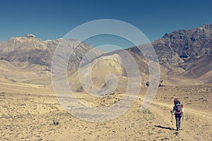 Female trekker walking alone though mountain desert.