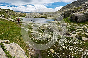 Female trekker walking along mountain lake.