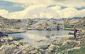 Female trekker walking along mountain lake.