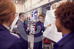 Female Tutor By Whiteboard With Students Teaching Auto Mechanic Apprenticeship At College