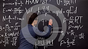 Female tutor writing formula on chalkboard, mathematics lecture, exact sciences