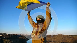 Female ukrainian army soldier holding waving flag of Ukraine. Girl in military uniform lifted up yellow-blue flag
