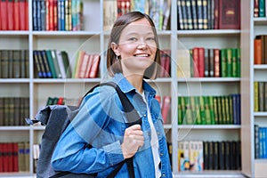 Female university student with backpack, inside library of educational building