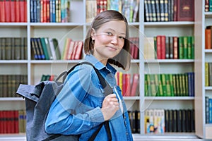 Female university student with backpack, inside library of educational building