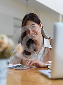 Female university student doing assignment with digital devices in cafe