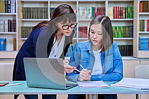 Female university student with teacher preparing for exam, inside library