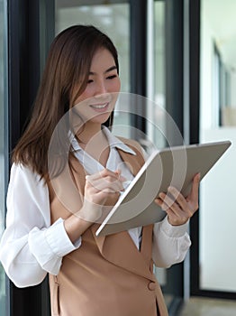 Female university using digital tablet to preparing presentation in library