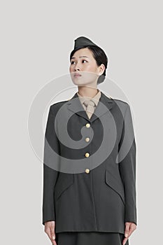 Female US military officer standing in attention as she looks away over gray background