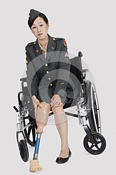 Female US military officer in wheelchair holding artificial limb over gray backgrounds