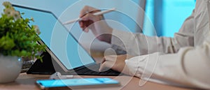 Female using blank screen tablet with stylus and keyboard on office desk