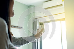 Female using remote control to open air conditioning in bedroom,Close up