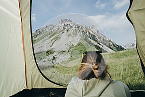 Female vacationer camper in tent Looking At mountain view in Mon