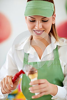 Female vendor in confectionery putting ice cream ball in cone