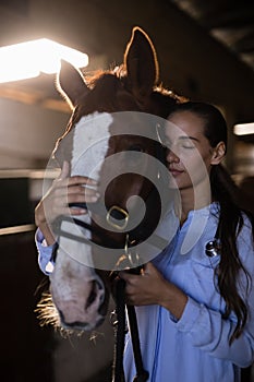 Female vet with eyes closed standing by horse at stable