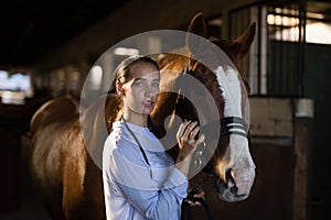 Female vet stroking horse at stable