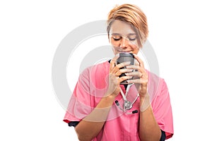 Female vet wearing pink scrub savoring to go cup of coffee