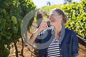 Female vintner talking on mobile phone in vineyard