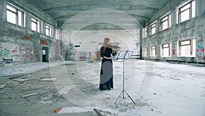 Female violinist plays a violin in an abandoned building.