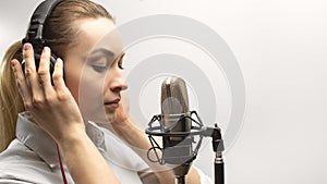 Female vocal recording. Young girl with microphone and headphones in recording studio. Recording of vocal, blogger, reading text,