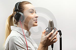 Female vocal recording. Young girl with microphone and headphones in recording studio. Recording of vocal, blogger, reading text,