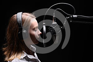 Female vocal recording. Young girl with microphone and headphones in recording studio. Recording of vocal, blogger, reading text,