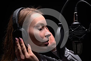 Female vocal recording. Young girl with microphone and headphones in recording studio. Recording of vocal, blogger, reading text,