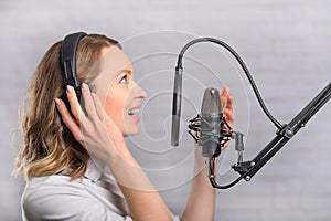 Female vocal recording. Young girl with microphone and headphones in recording studio. Recording of vocal, blogger, reading text,