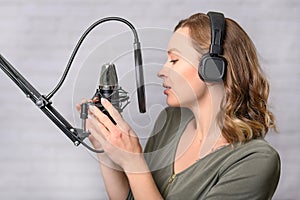 Female vocal recording. Young girl with microphone and headphones in recording studio. Recording of vocal, blogger, reading text,