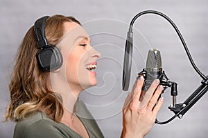 Female vocal recording. Young girl with microphone and headphones in recording studio. Recording of vocal, blogger, reading text,